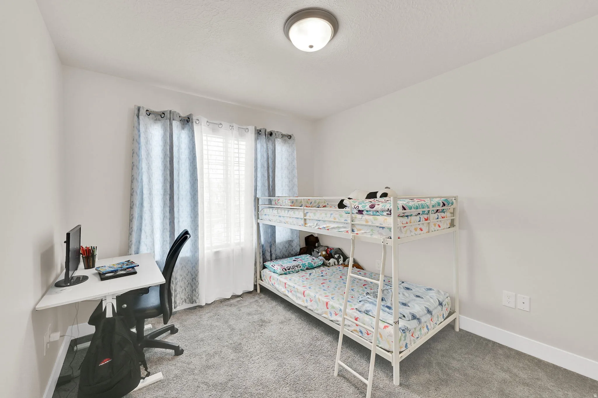 Bedroom with an office area and light colored carpet