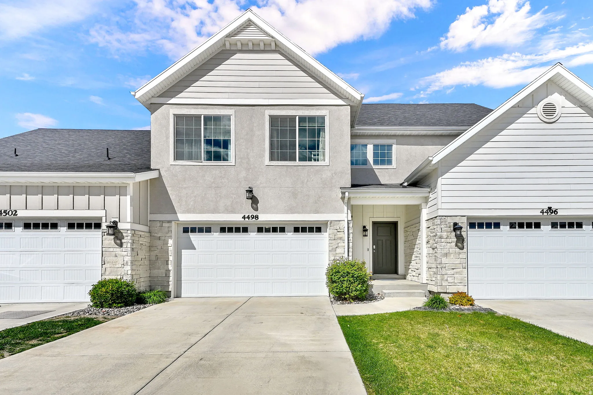 View of front of property with stone siding, roof with shingles, driveway, board and batten siding, and an attached garage