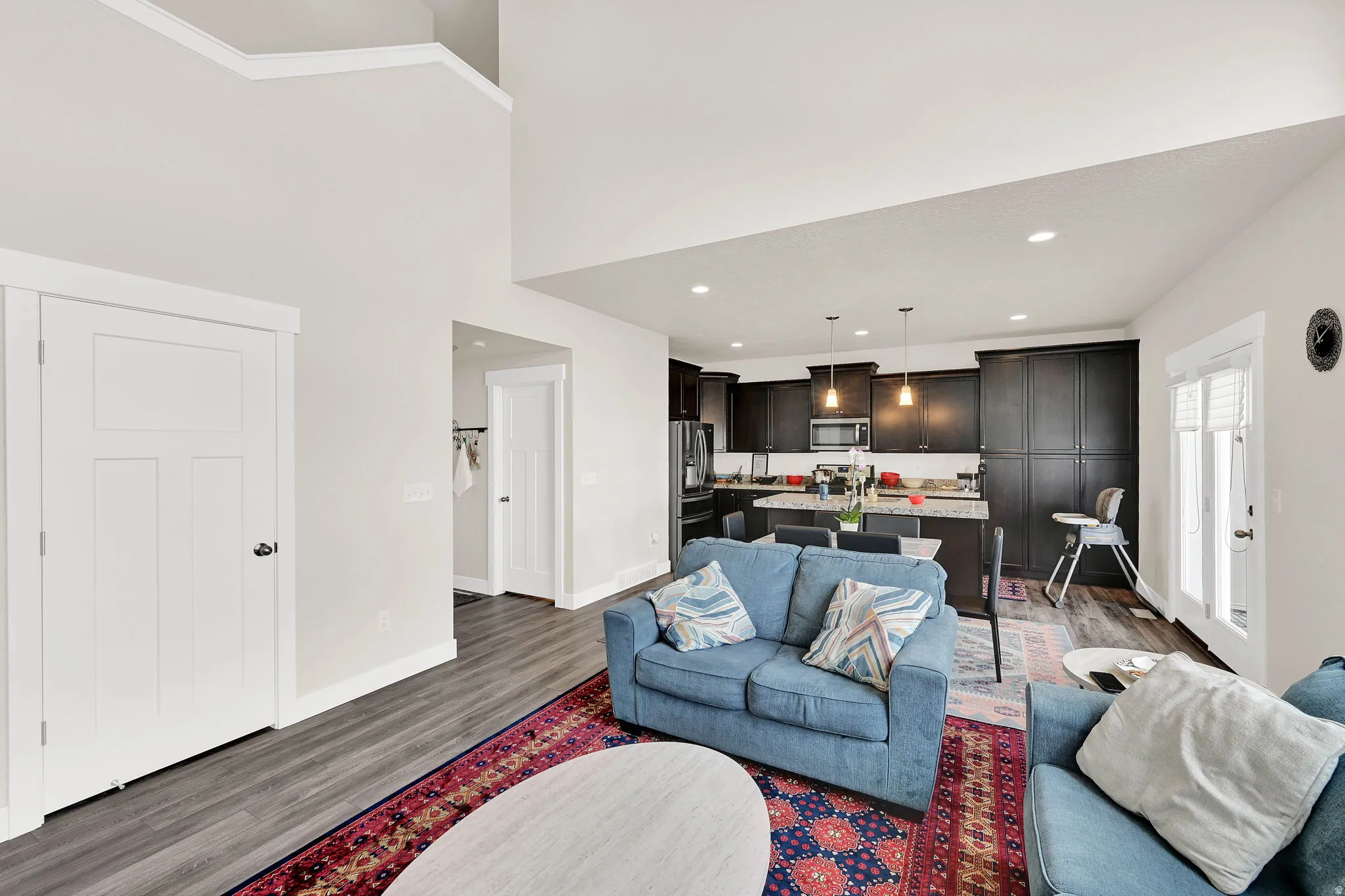 Living area with dark wood-style floors, recessed lighting, and a high ceiling