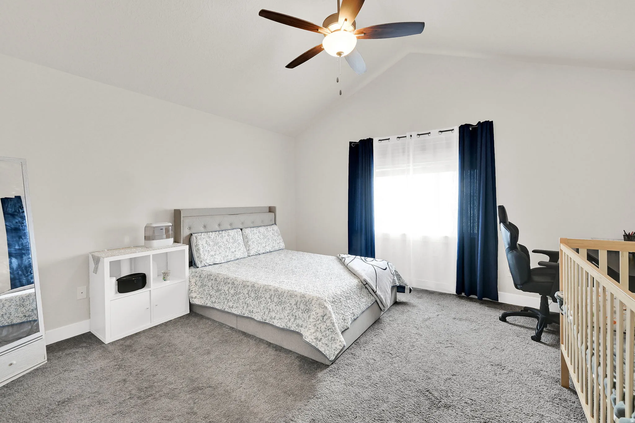 Carpeted bedroom with a desk and a ceiling fan