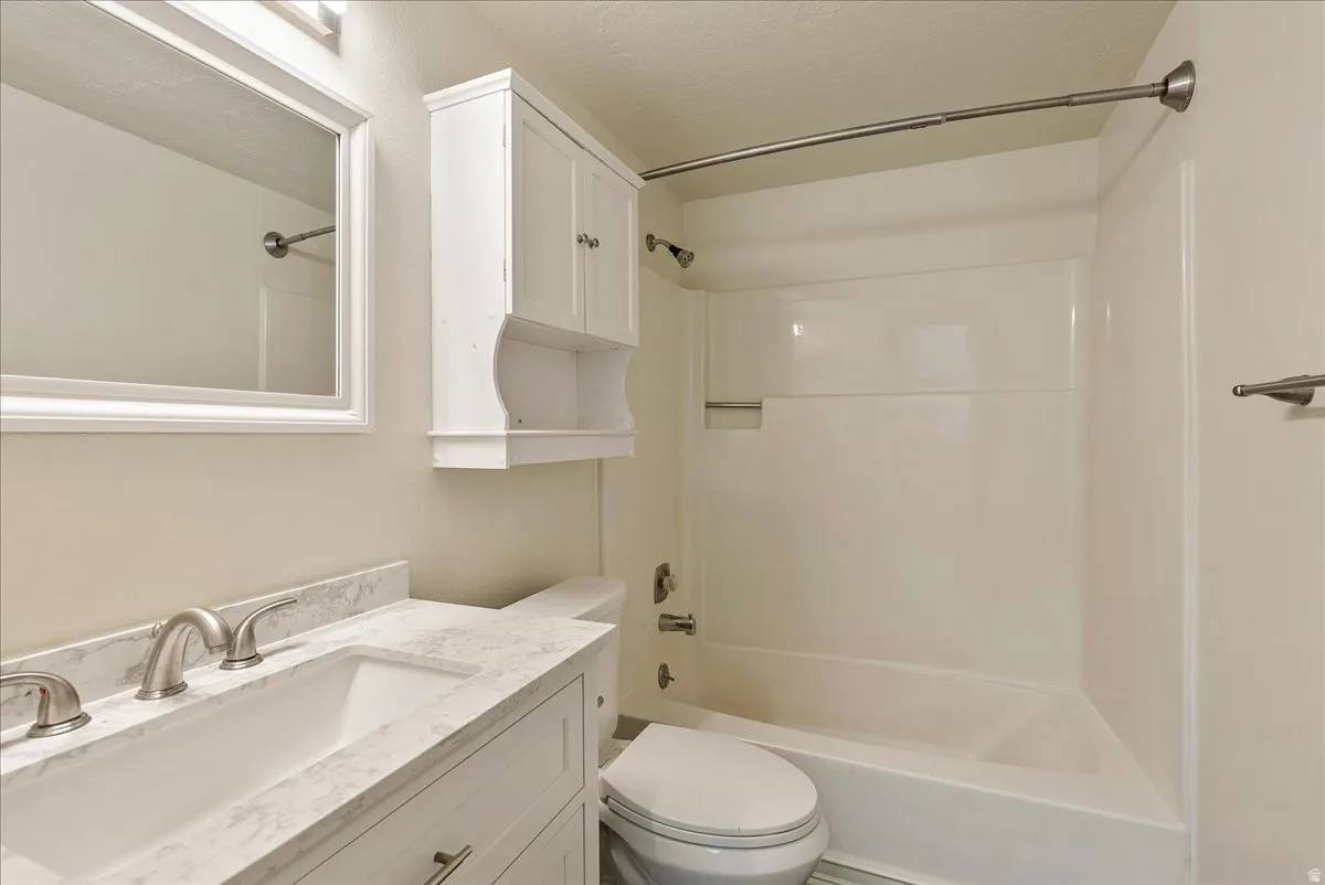 Bathroom featuring vanity, shower / tub combination, and a textured ceiling