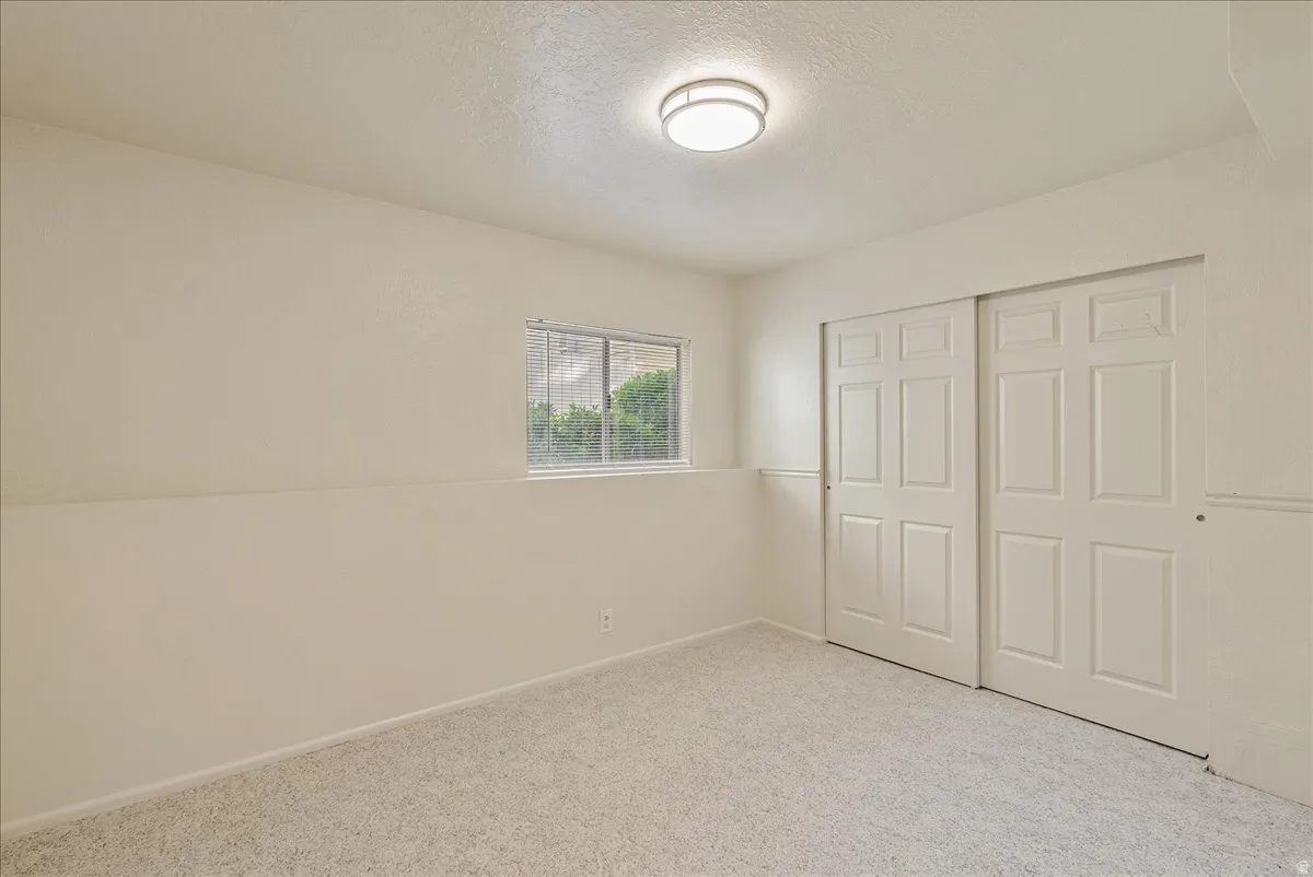 Unfurnished bedroom featuring carpet floors, a textured ceiling, and a closet