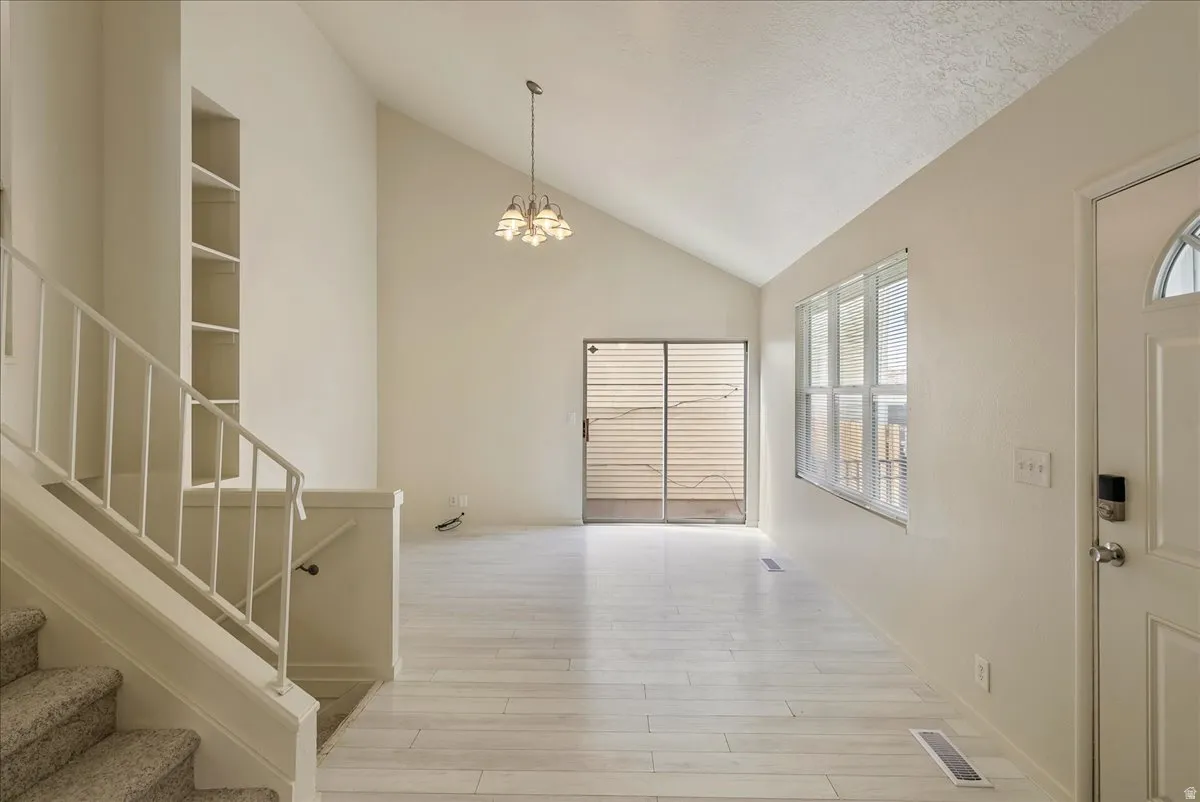 Foyer with lofted ceiling, light wood finished floors, and suspended lighting