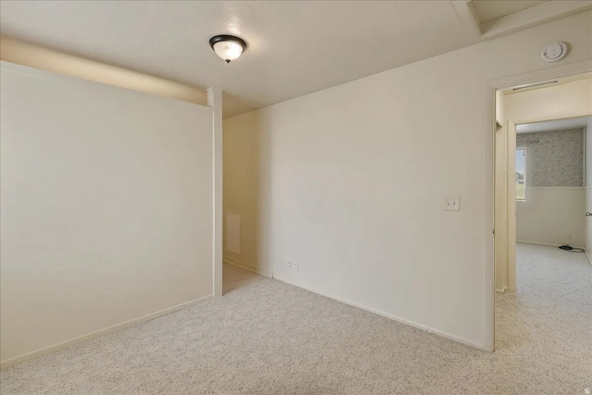 Empty room featuring light colored carpet and baseboards