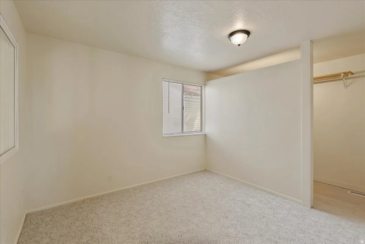 Unfurnished bedroom with a closet, a textured ceiling, and light colored carpet