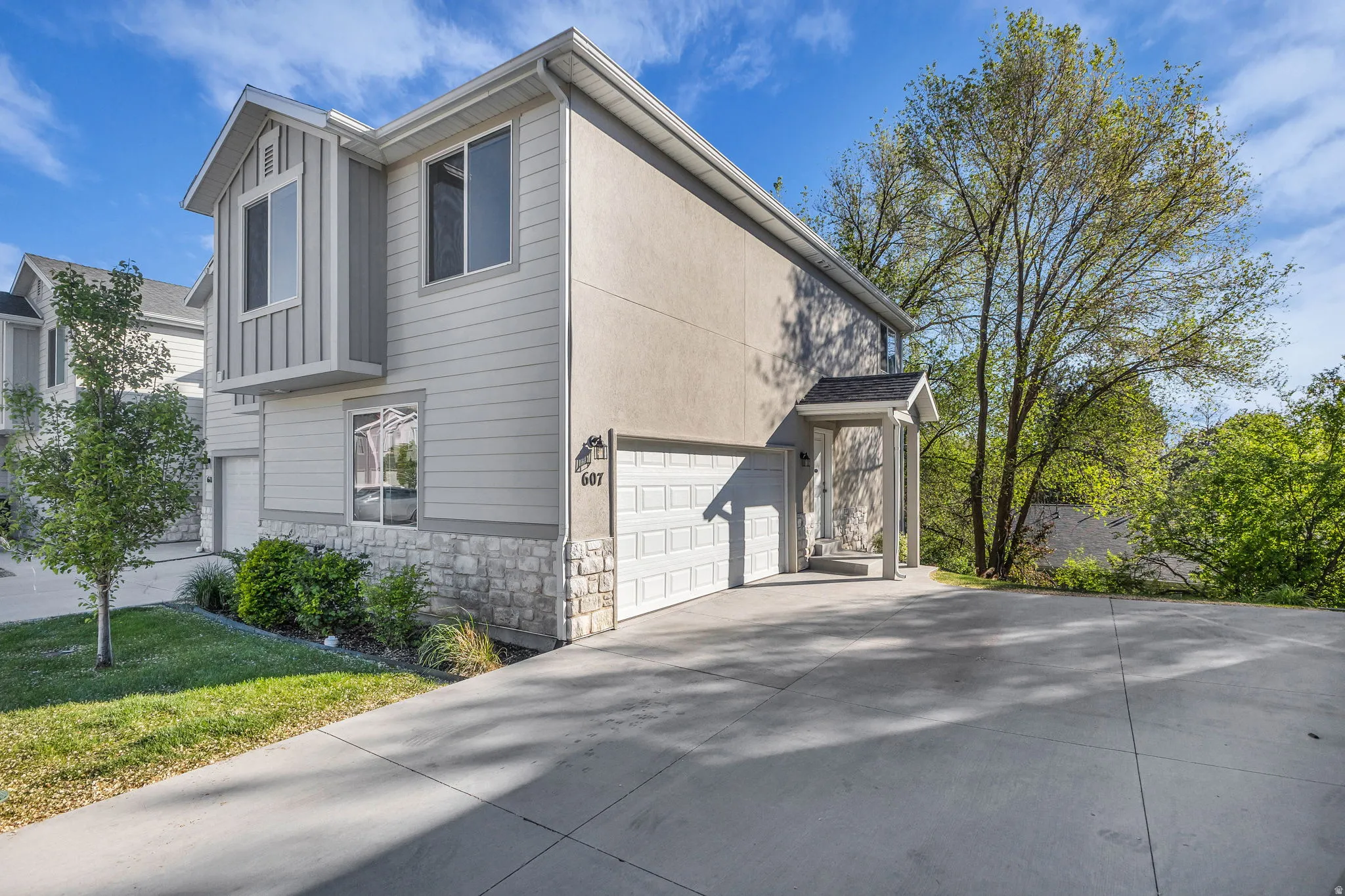 View of side of property with stone siding, a garage, and concrete driveway