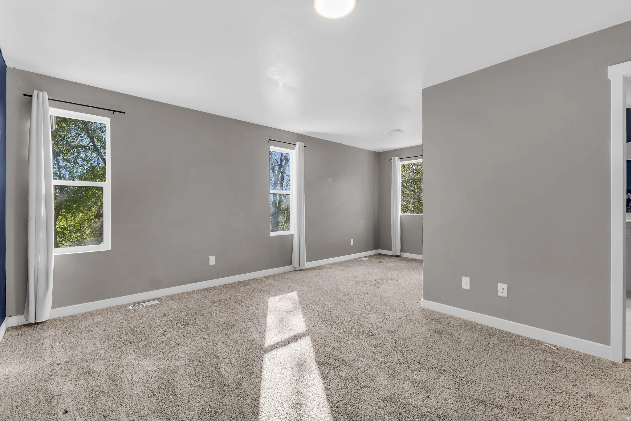 Empty room with light colored carpet and plenty of natural light