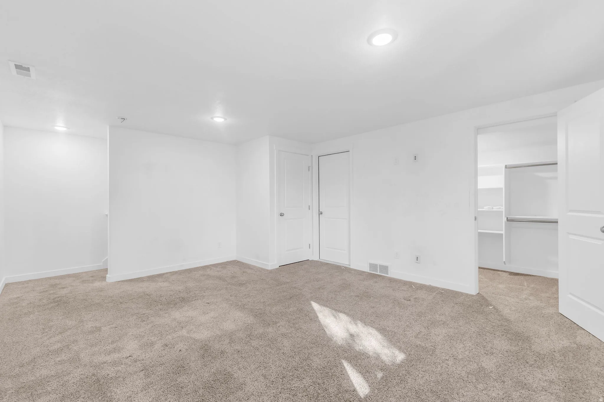 Unfurnished bedroom with a walk in closet and light colored carpet