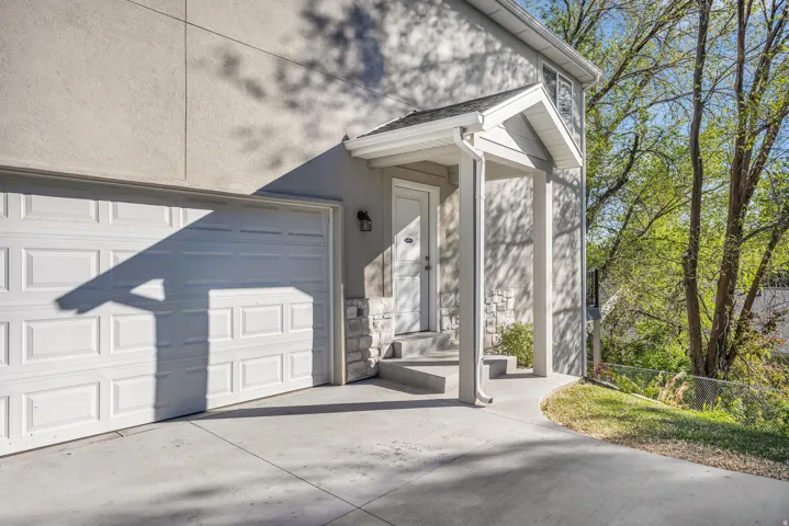 Doorway to property with driveway, stucco siding, and a shingled roof