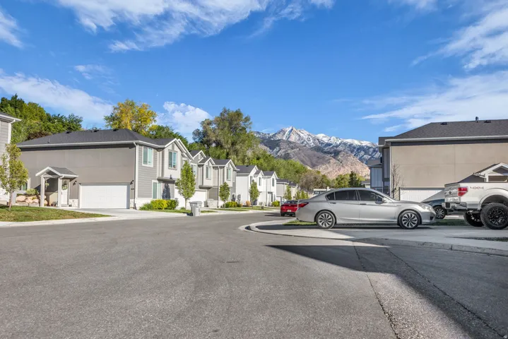 View of asphalt road featuring a residential view, a mountain view, curbs, and sidewalks