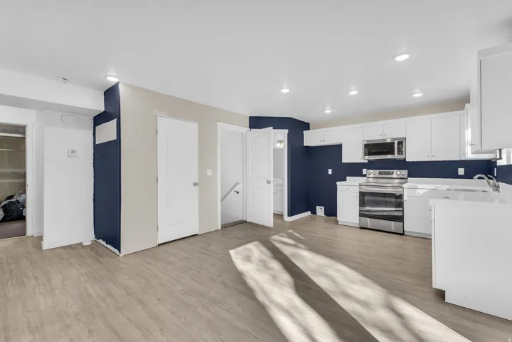 Kitchen with stainless steel appliances, white cabinetry, light wood finished floors, and recessed lighting