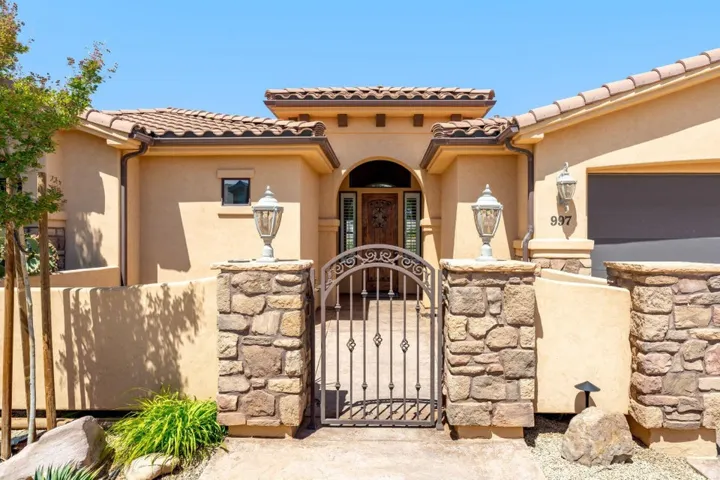 Mediterranean / spanish-style home with a gate, a fenced front yard, stucco siding, and a tiled roof