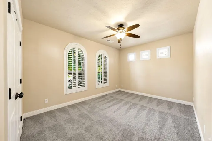 Spare room with light carpet, a ceiling fan, and a textured ceiling