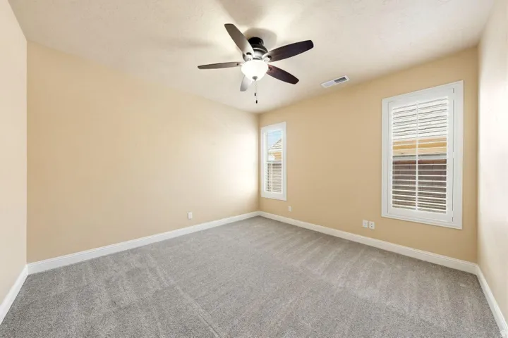 Empty room featuring light colored carpet and a ceiling fan