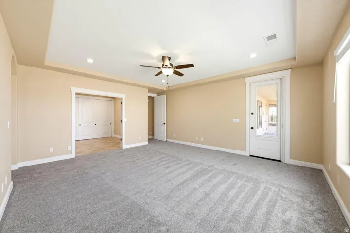 Unfurnished bedroom featuring recessed lighting, a tray ceiling, light colored carpet, and ceiling fan