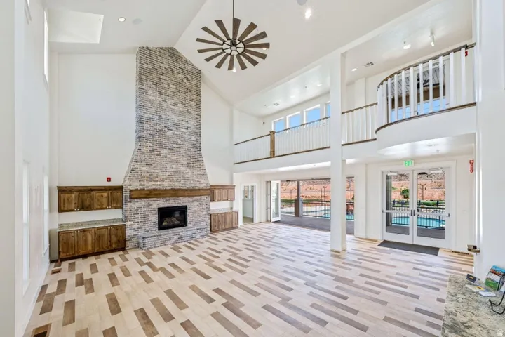 Unfurnished living room with french doors, a high ceiling, a brick fireplace, and recessed lighting