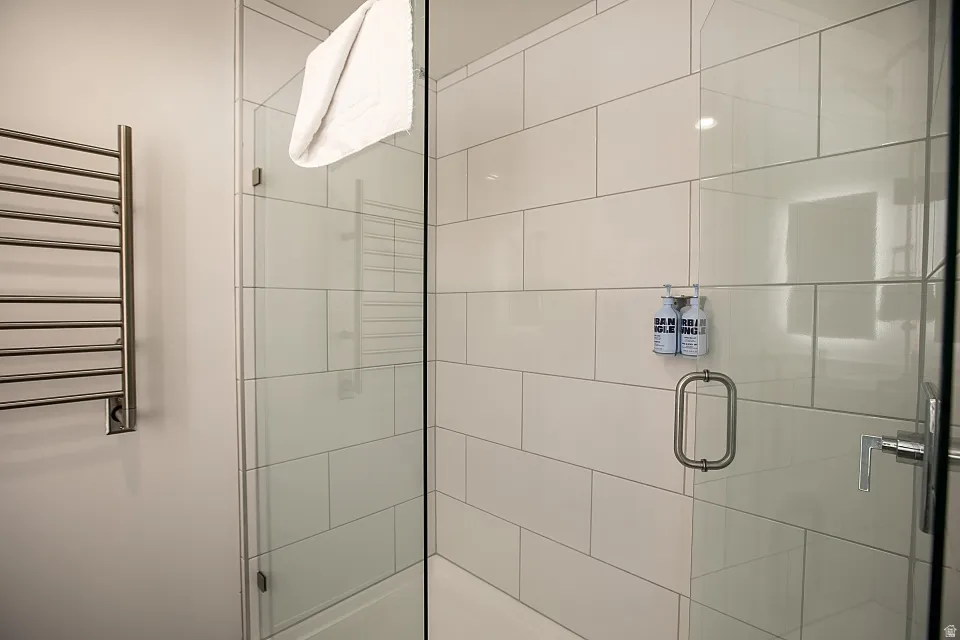 Full bath featuring a towel warmer, a shower stall, and radiator heating unit