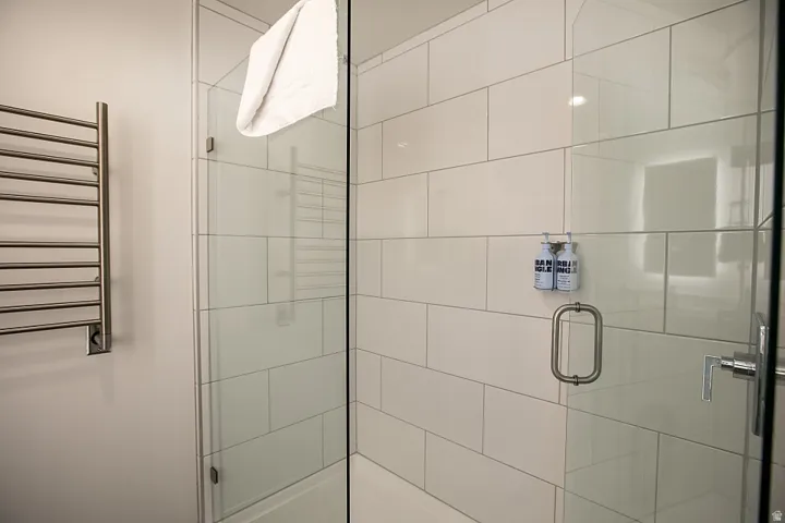 Full bath featuring a towel warmer, a shower stall, and radiator heating unit