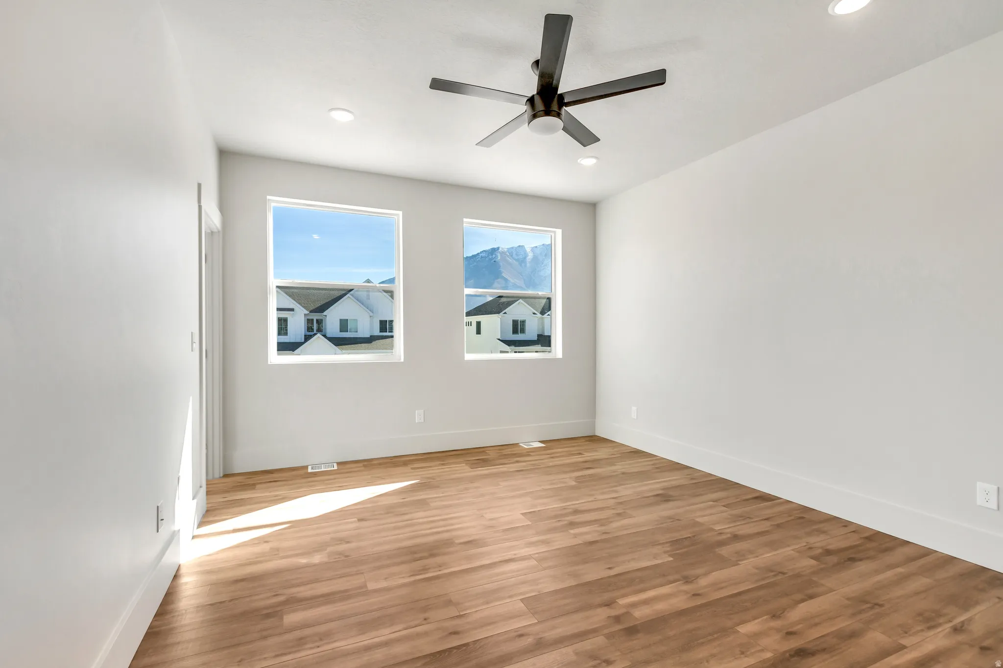 Empty room with light wood finished floors, ceiling fan, and recessed lighting
