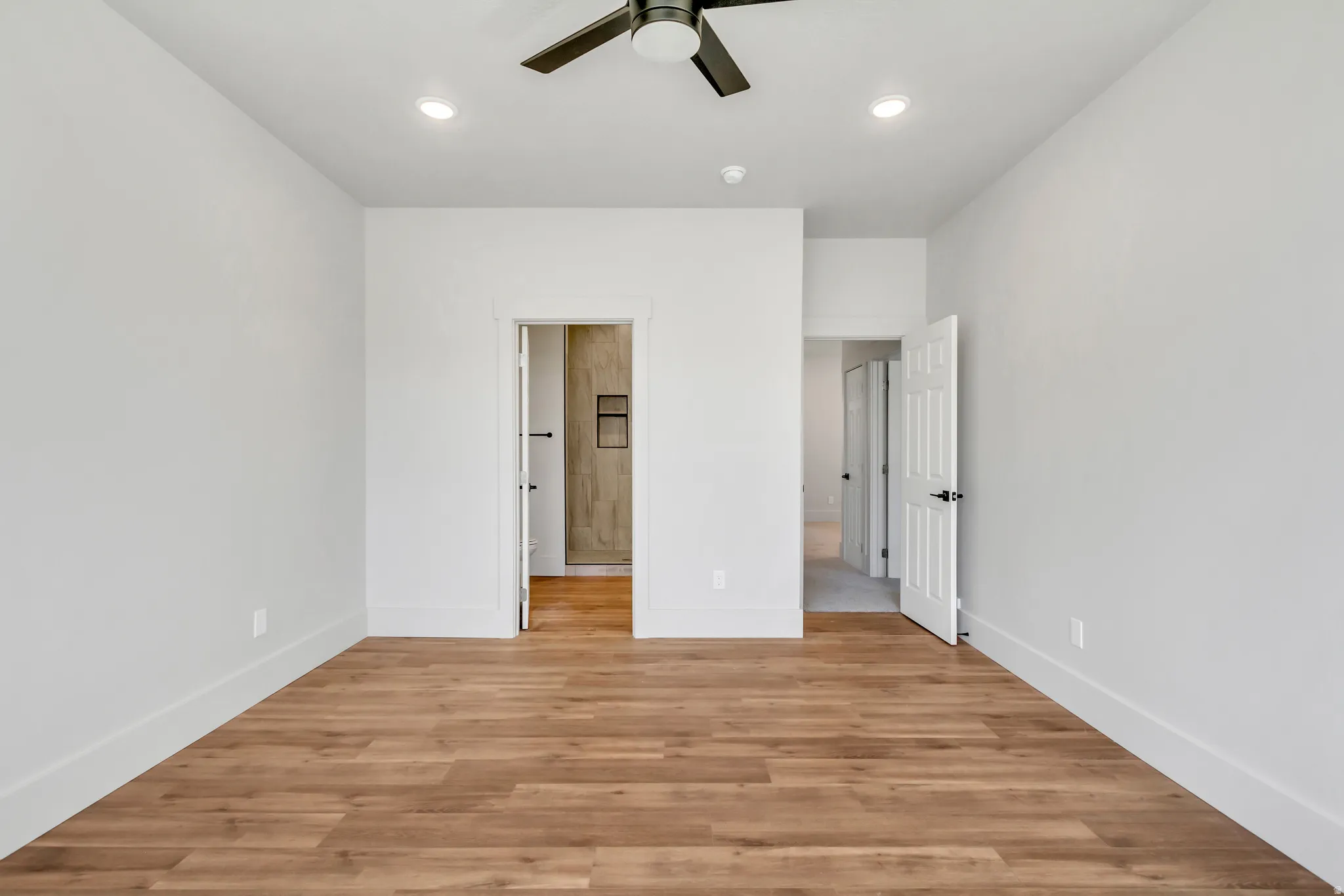 Unfurnished bedroom with light wood-type flooring, a ceiling fan, recessed lighting, and connected bathroom