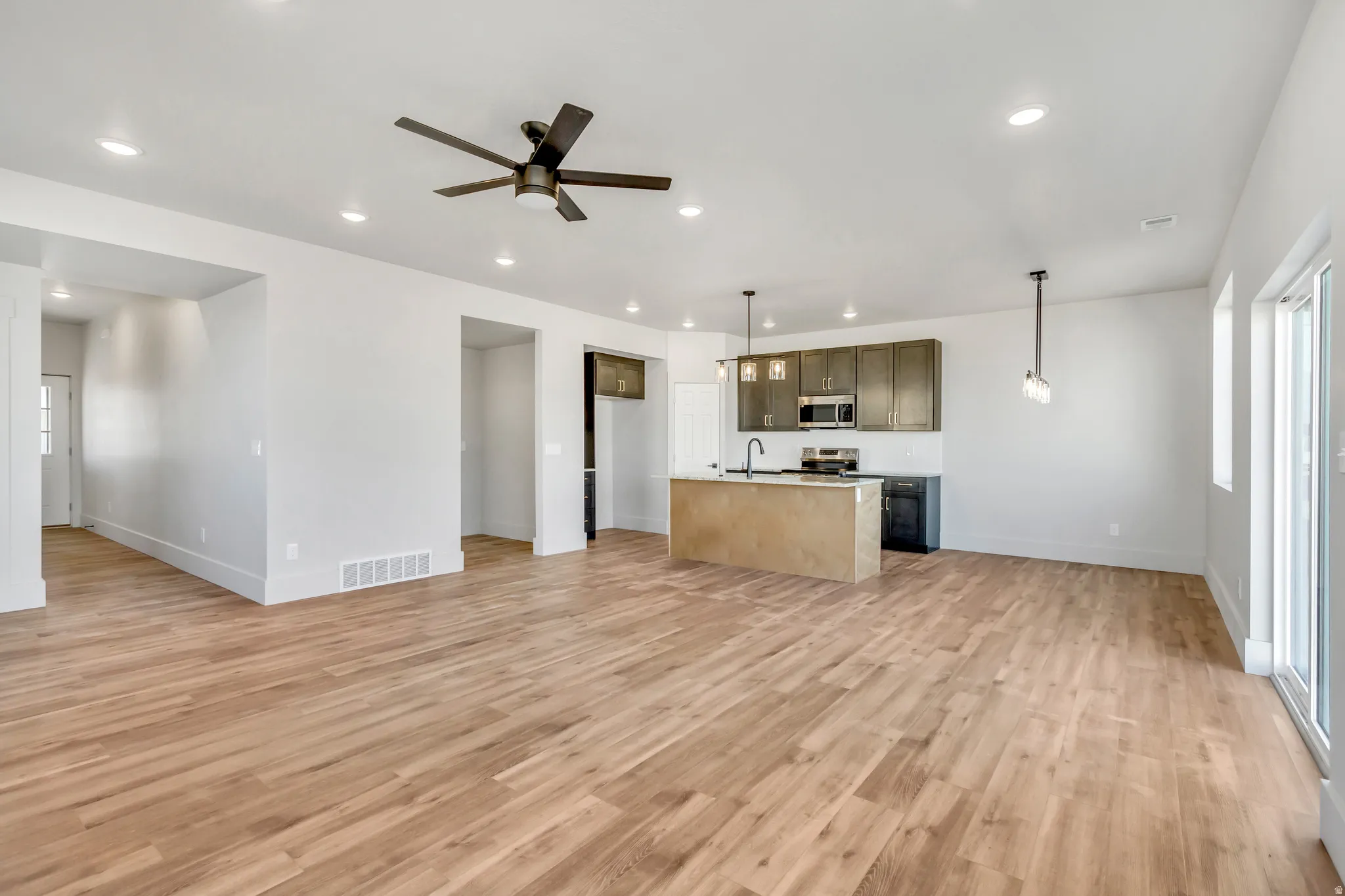 Unfurnished living room with ceiling fan, light wood-style floors, and recessed lighting