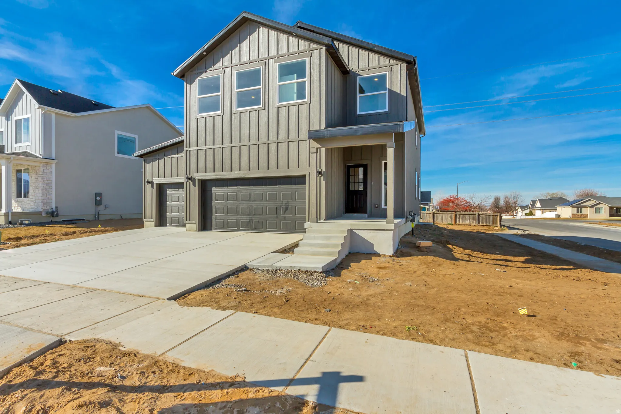View of front of property with board and batten siding, a garage, concrete driveway, and a residential view