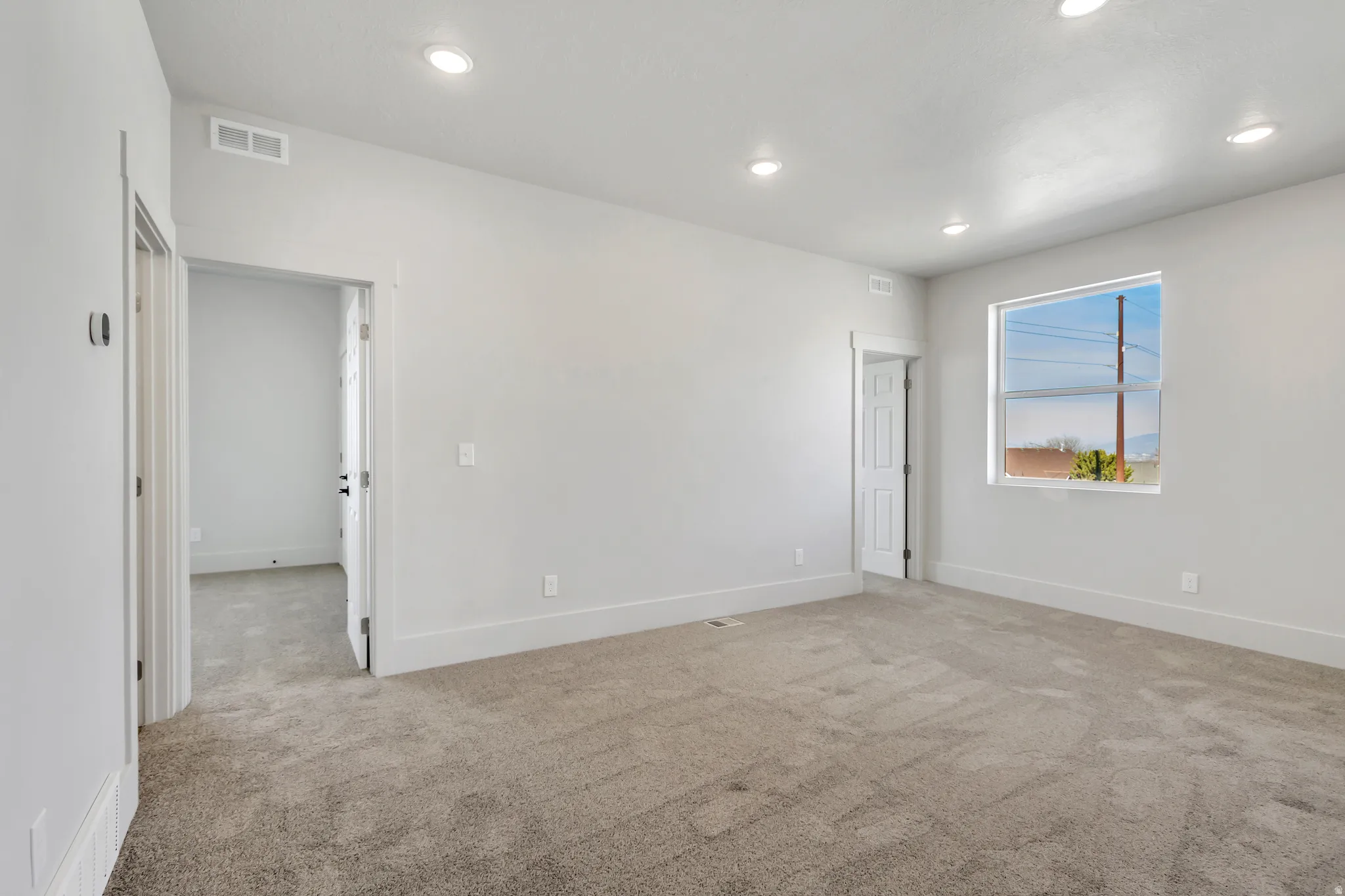 Empty room with light colored carpet and recessed lighting