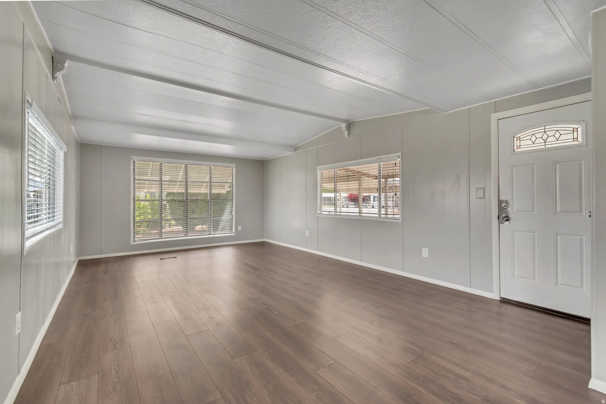 Entrance foyer featuring dark wood-style flooring and vaulted ceiling with beams