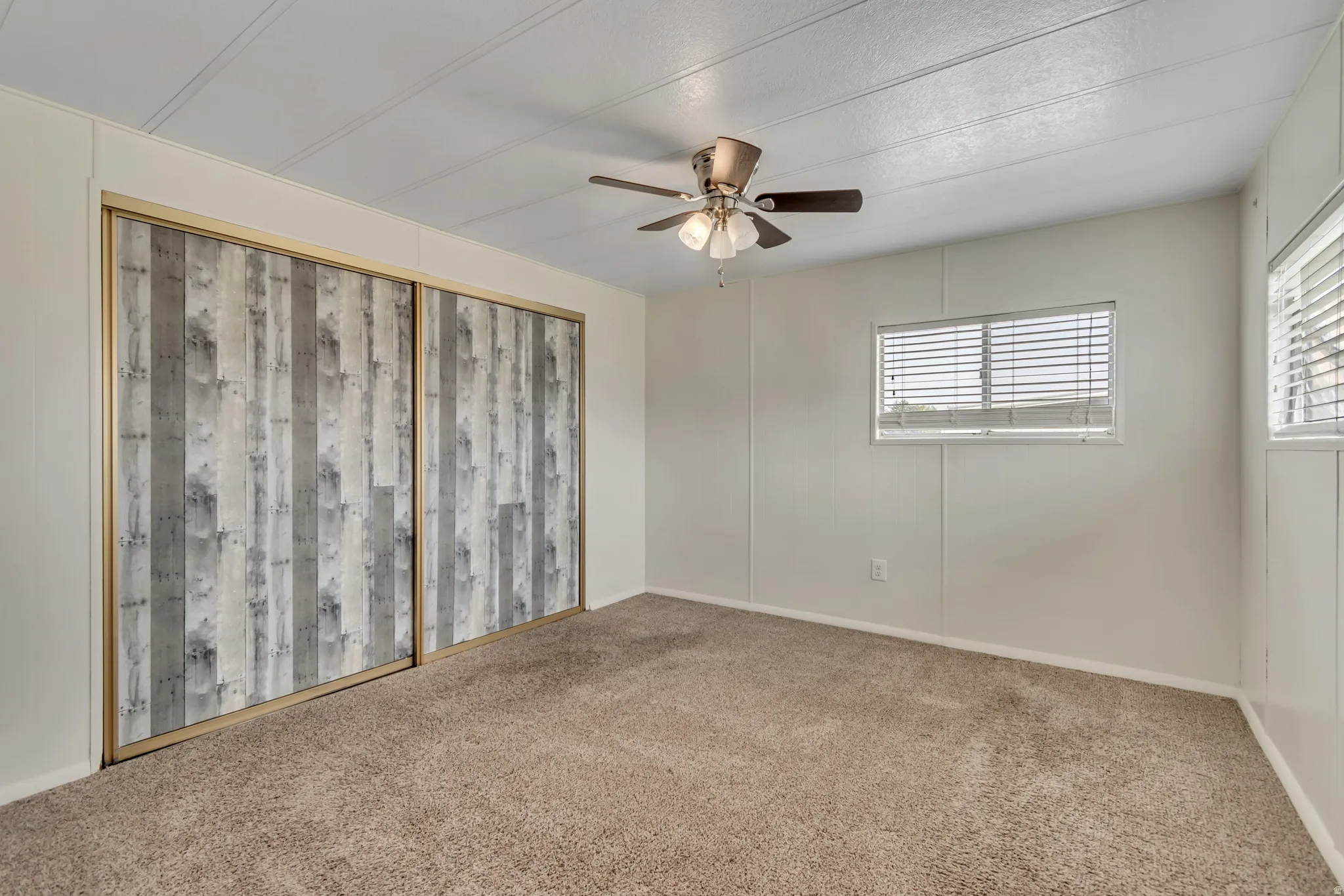 Carpeted spare room featuring ceiling fan