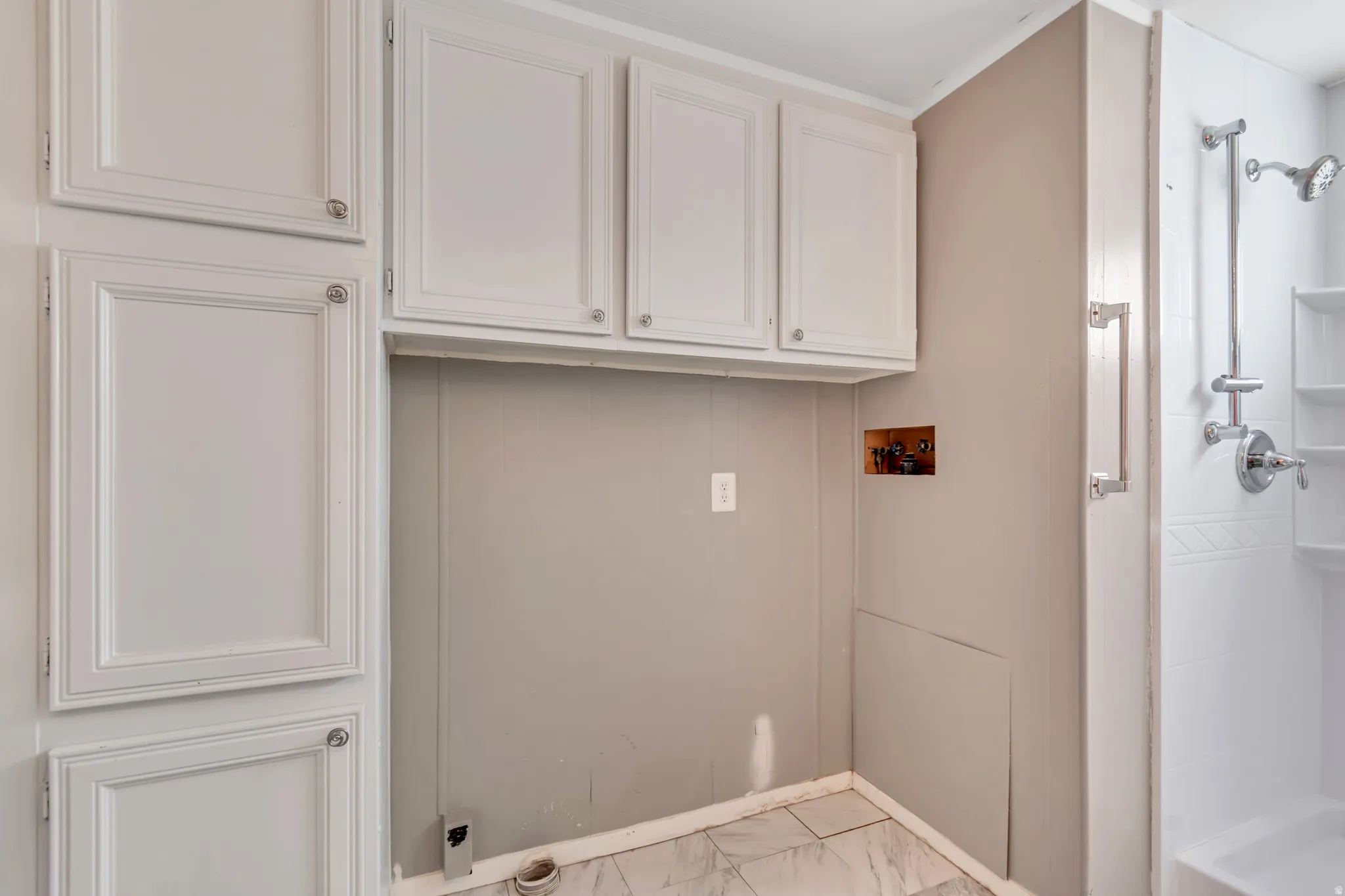 Laundry room featuring light marble finish flooring, hookup for a washing machine, and cabinet space