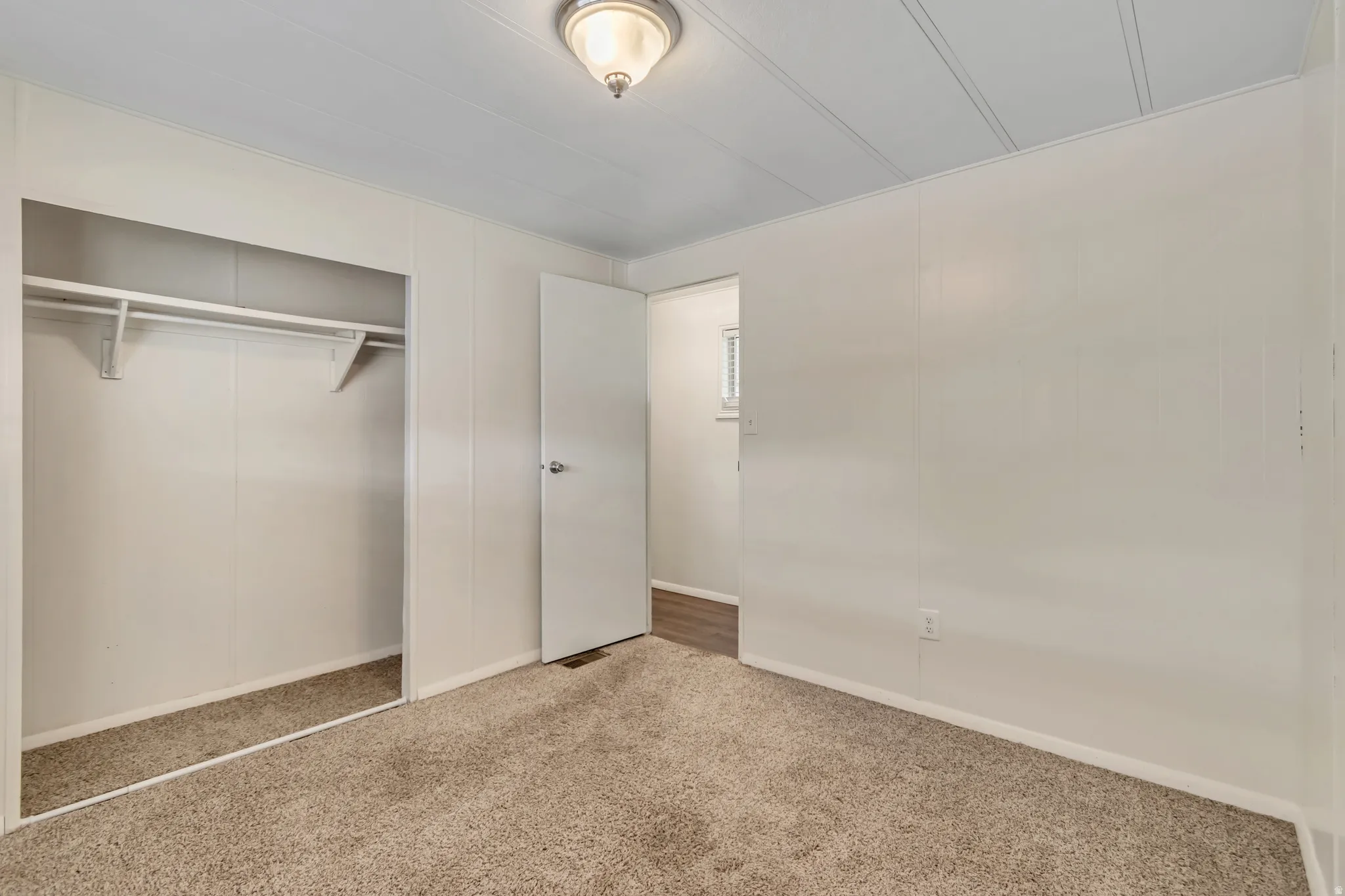 Unfurnished bedroom featuring carpet floors, a closet, and a decorative wall