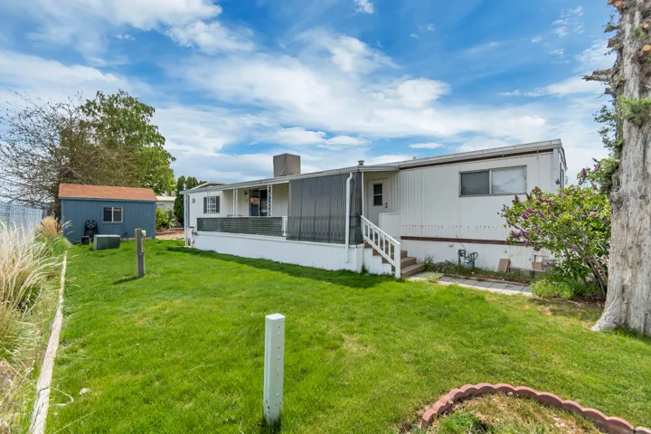 Rear view of house with a lawn, an outdoor structure, a chimney, and covered porch