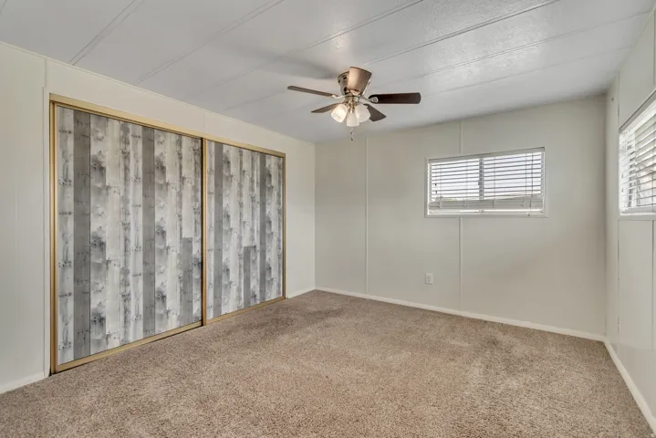Carpeted spare room featuring ceiling fan