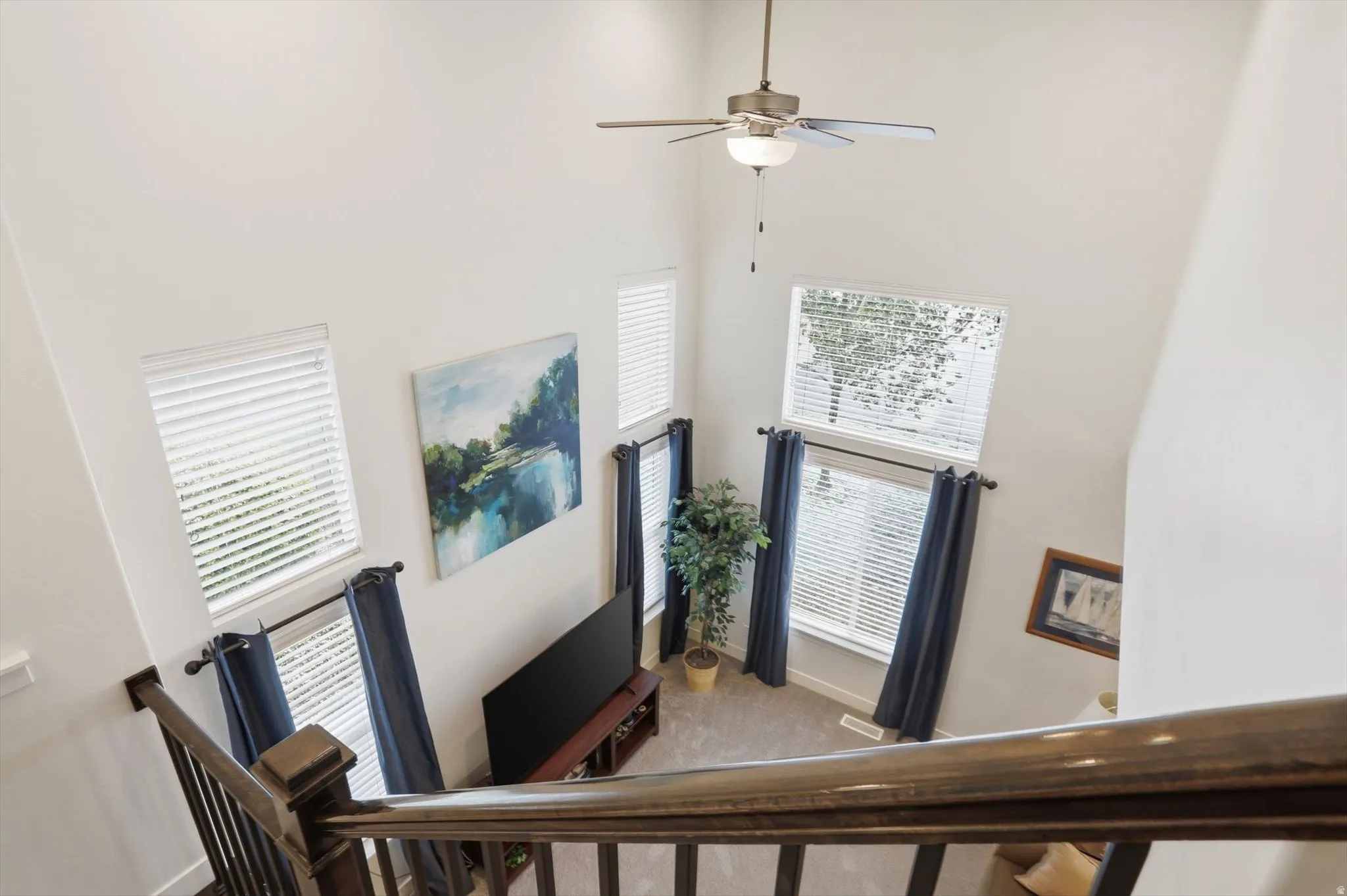 Foyer with a high ceiling, ceiling fan, carpet floors, and plenty of natural light