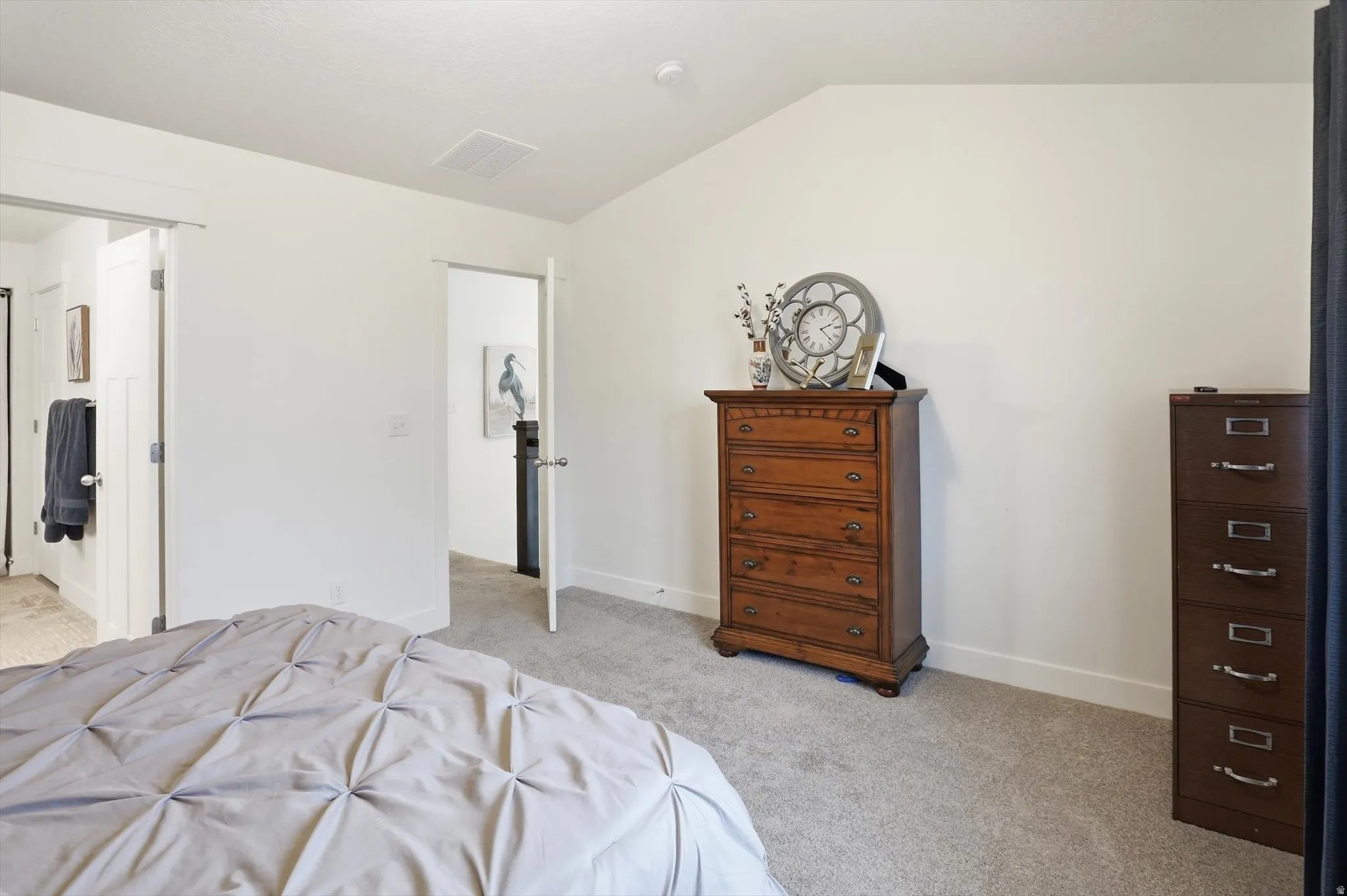 Bedroom featuring light colored carpet and vaulted ceiling