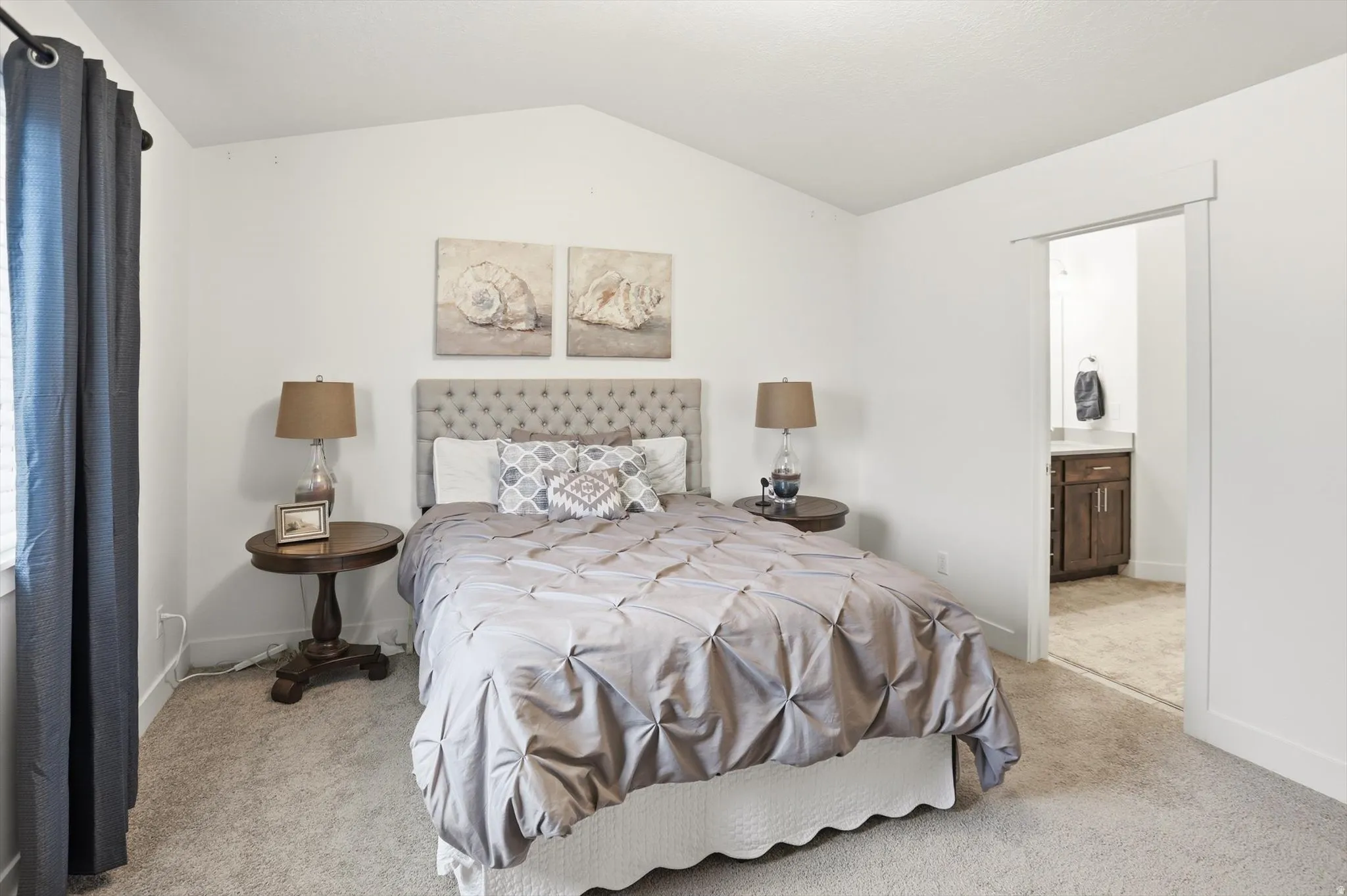 Carpeted bedroom featuring lofted ceiling and ensuite bath