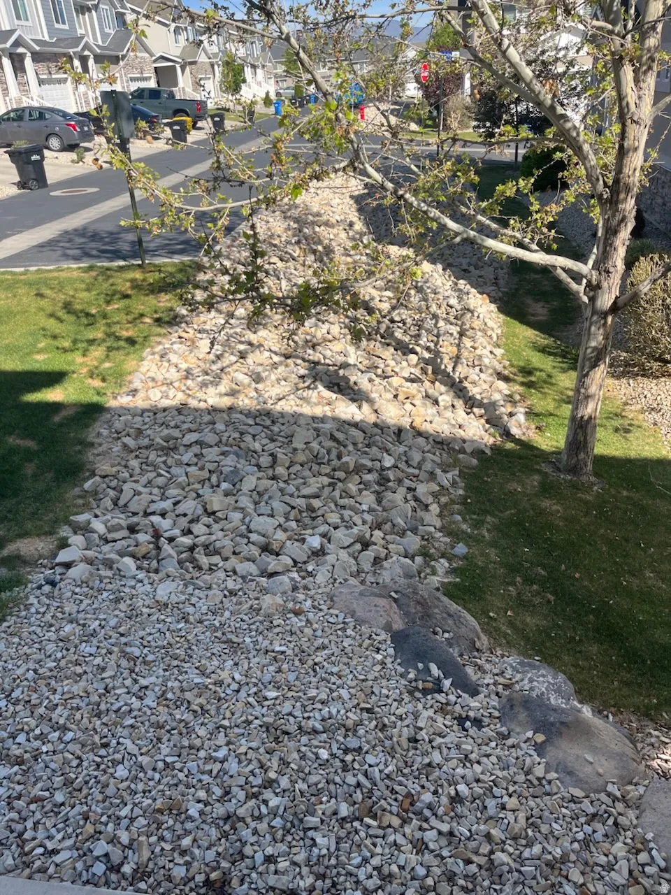 Landscaped rock feature with mixed stone sizes, bordering a manicured lawn