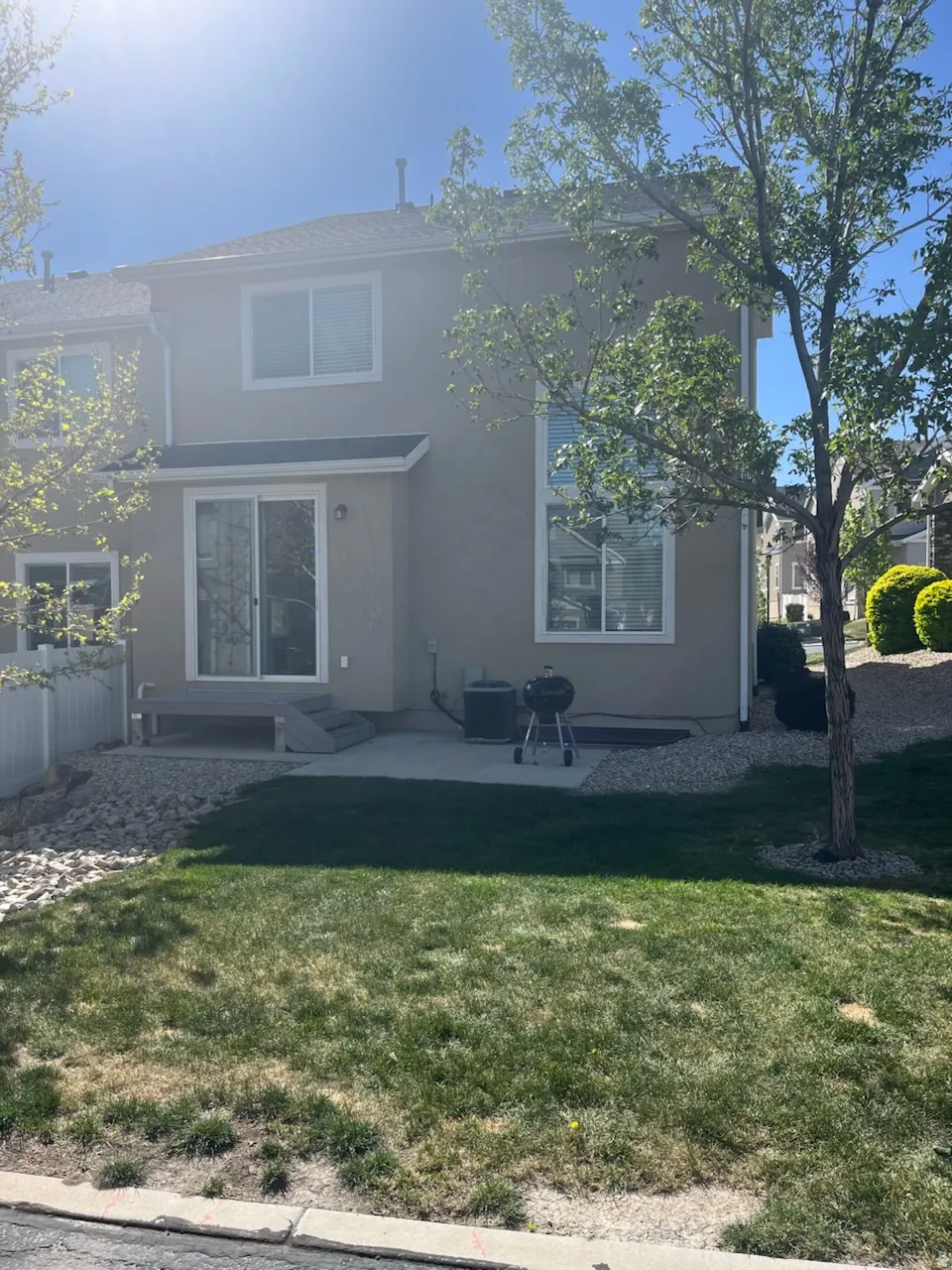 Rear exterior featuring a sliding glass door, a ground-level concrete patio, and a raised composite deck