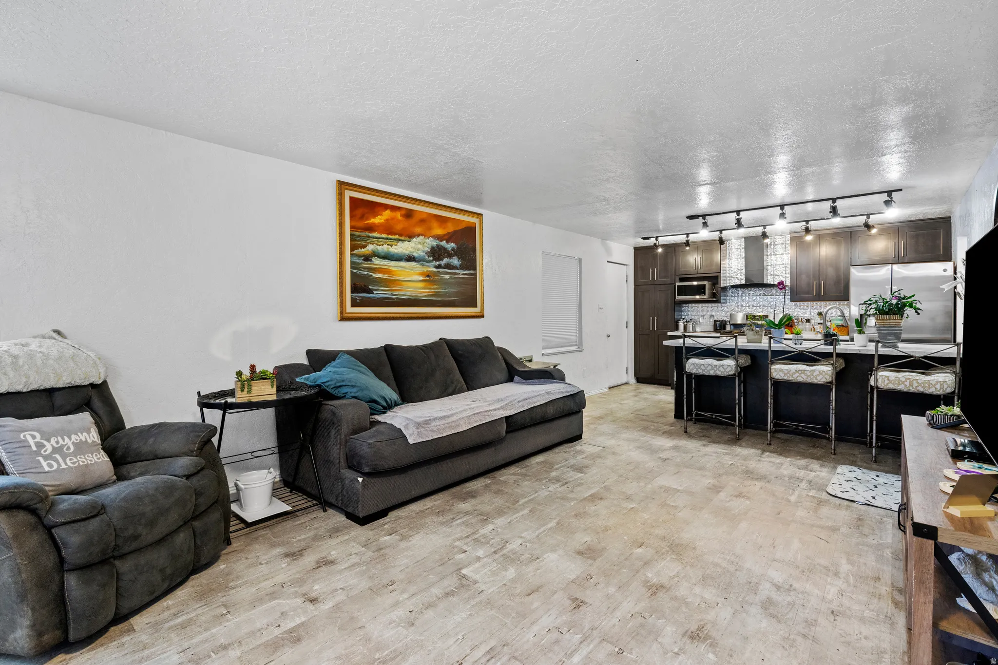 Living area with a textured ceiling and light wood-type flooring