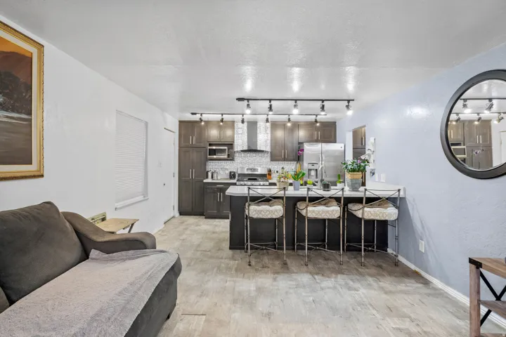 Kitchen with a kitchen breakfast bar, decorative backsplash, a textured ceiling, stainless steel appliances, and dark wood finish cabinets