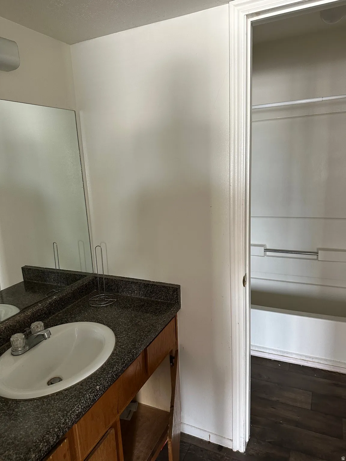 Bathroom with vanity, dark wood-style floors, and a textured ceiling