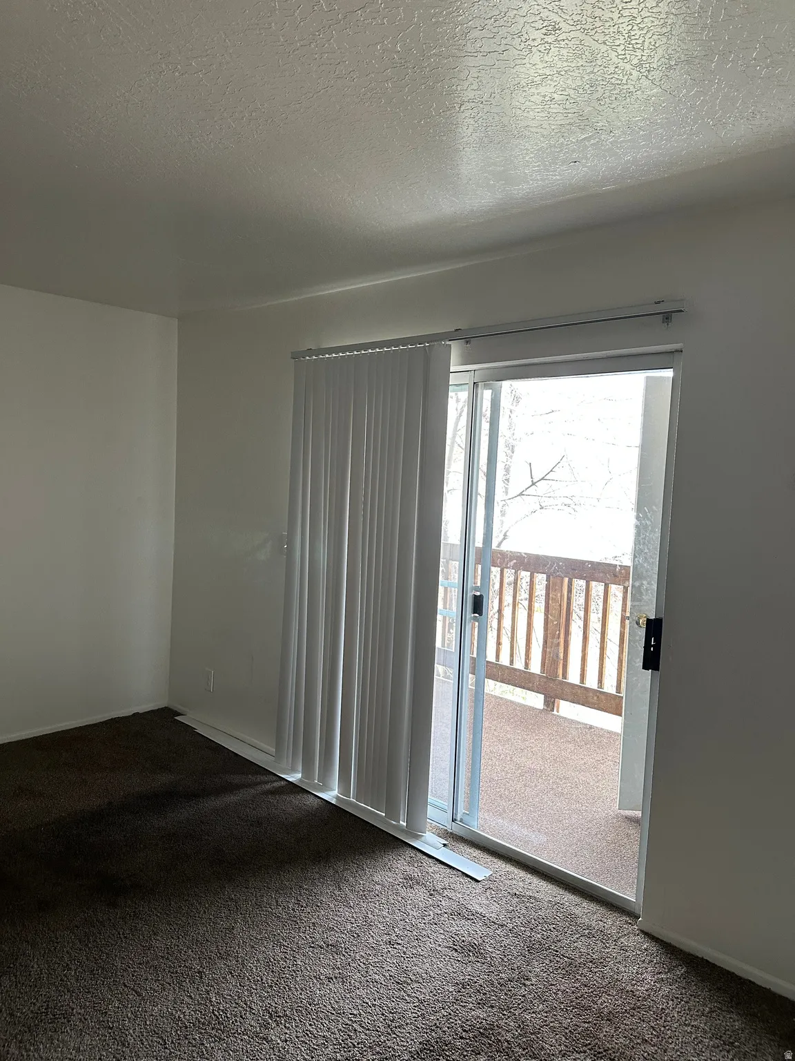 Spare room featuring dark colored carpet and a textured ceiling
