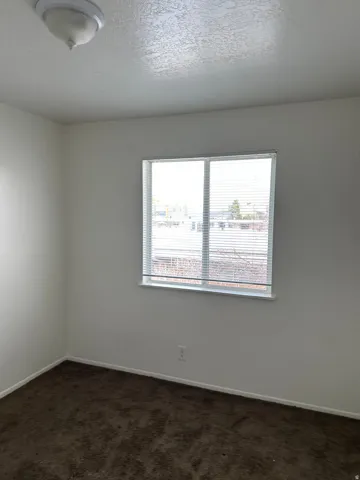 Empty room with dark carpet and a textured ceiling
