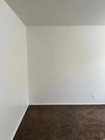 Unfurnished room with dark colored carpet and a textured ceiling