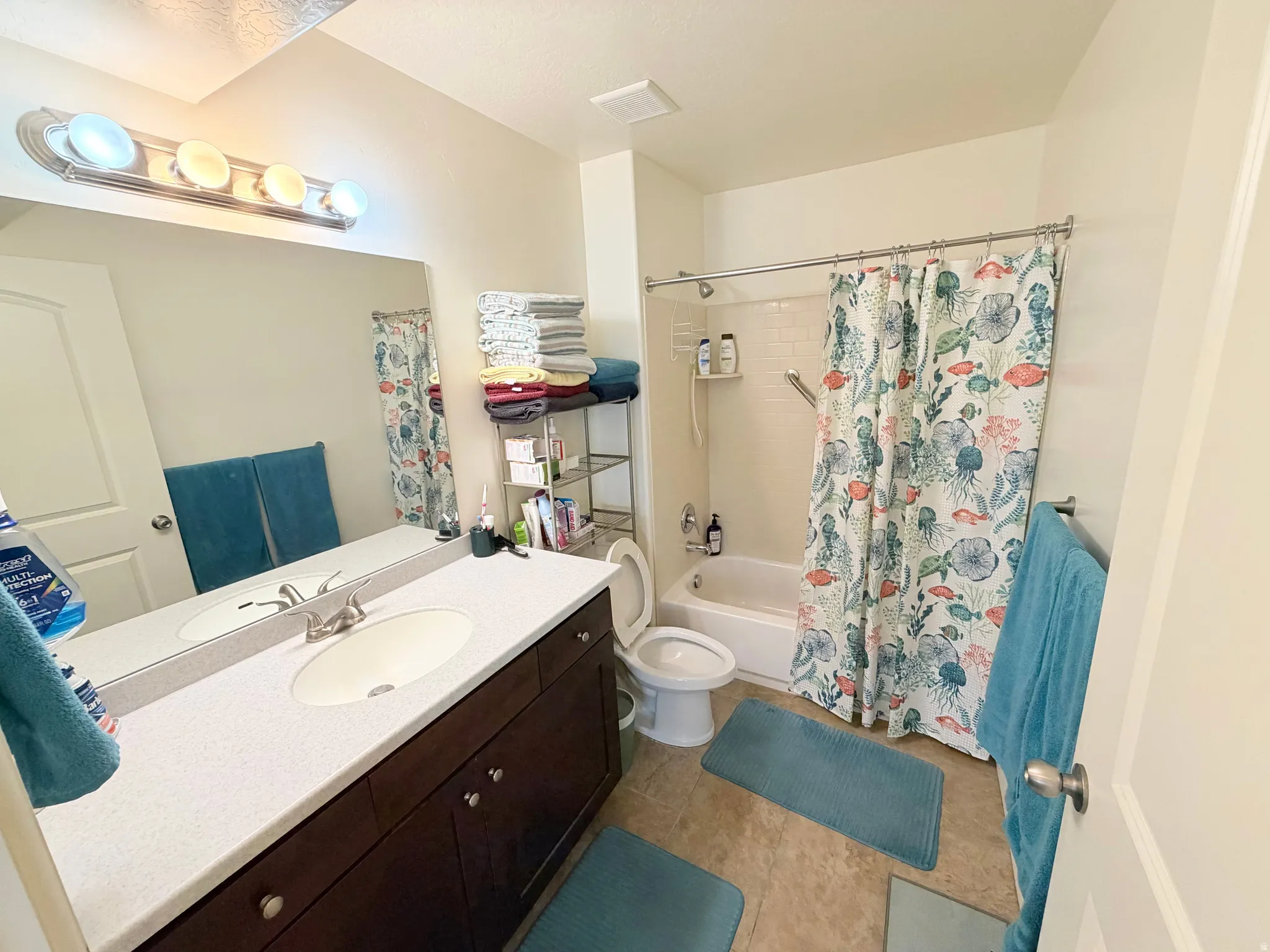 Full bathroom featuring a dark wood-finish vanity with a light-colored countertop, an undermount sink, and a large mirror