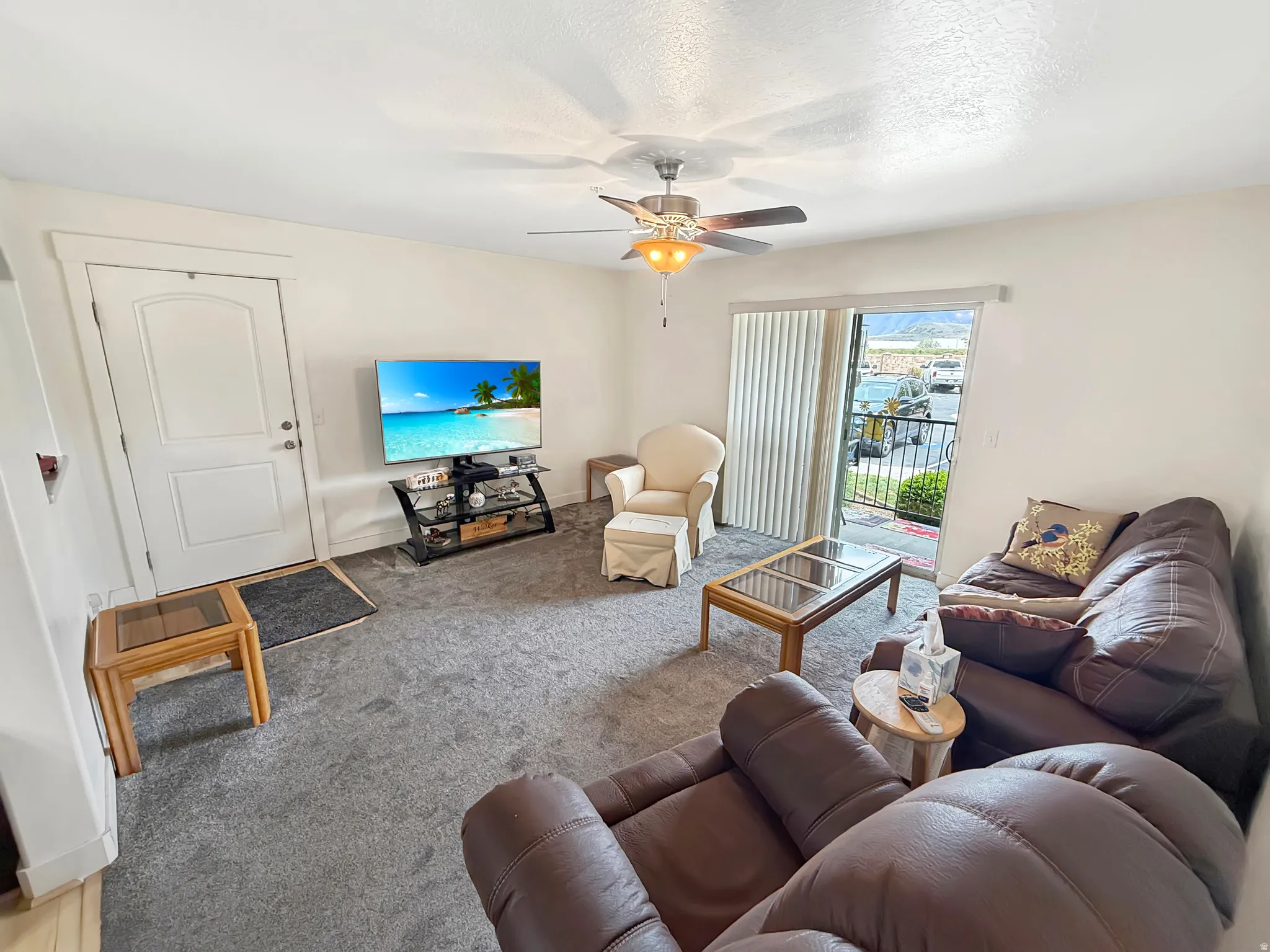 Living area with carpet floors, a ceiling fan, and a textured ceiling