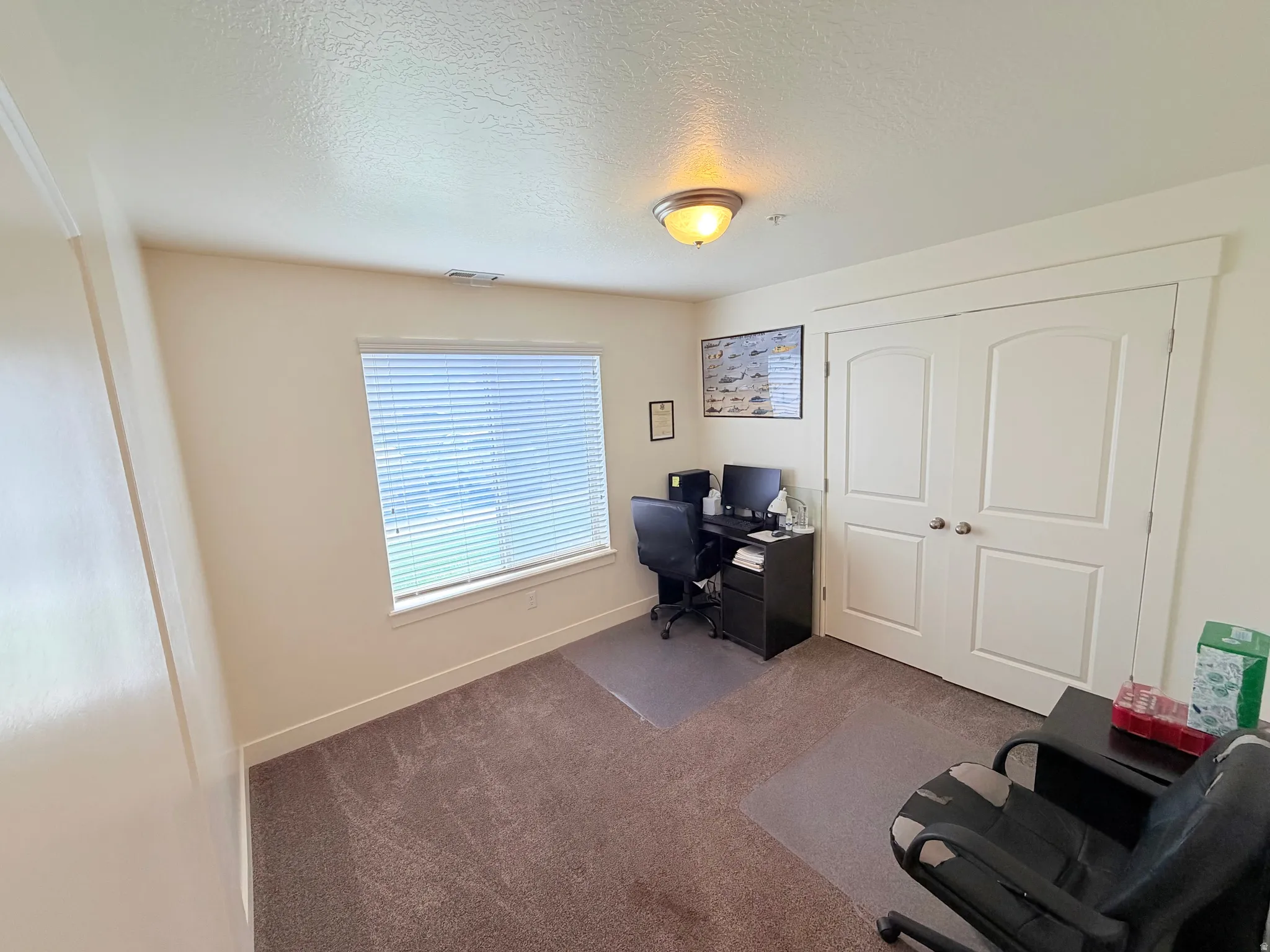 Carpeted room featuring a single window with horizontal blinds, a flush-mount ceiling light fixture, and double bi-fold doors with arched top panels