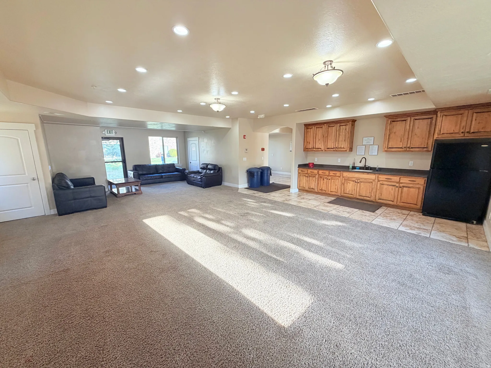 Kitchen featuring wood finish cabinetry, arched walkways, freestanding refrigerator, open floor plan, and light carpet