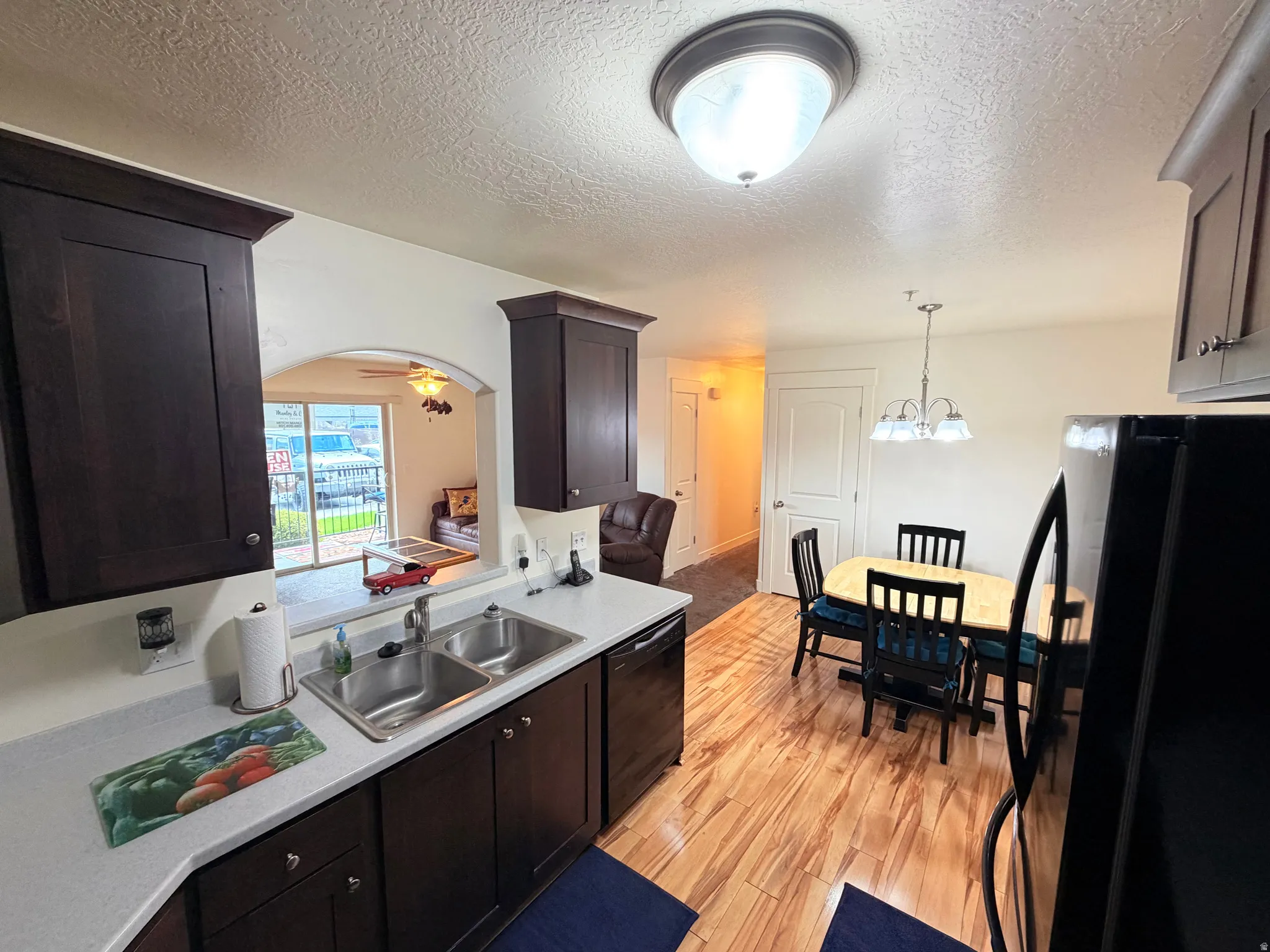 Kitchen featuring dark wood cabinetry, light-toned countertops, and a double stainless steel sink