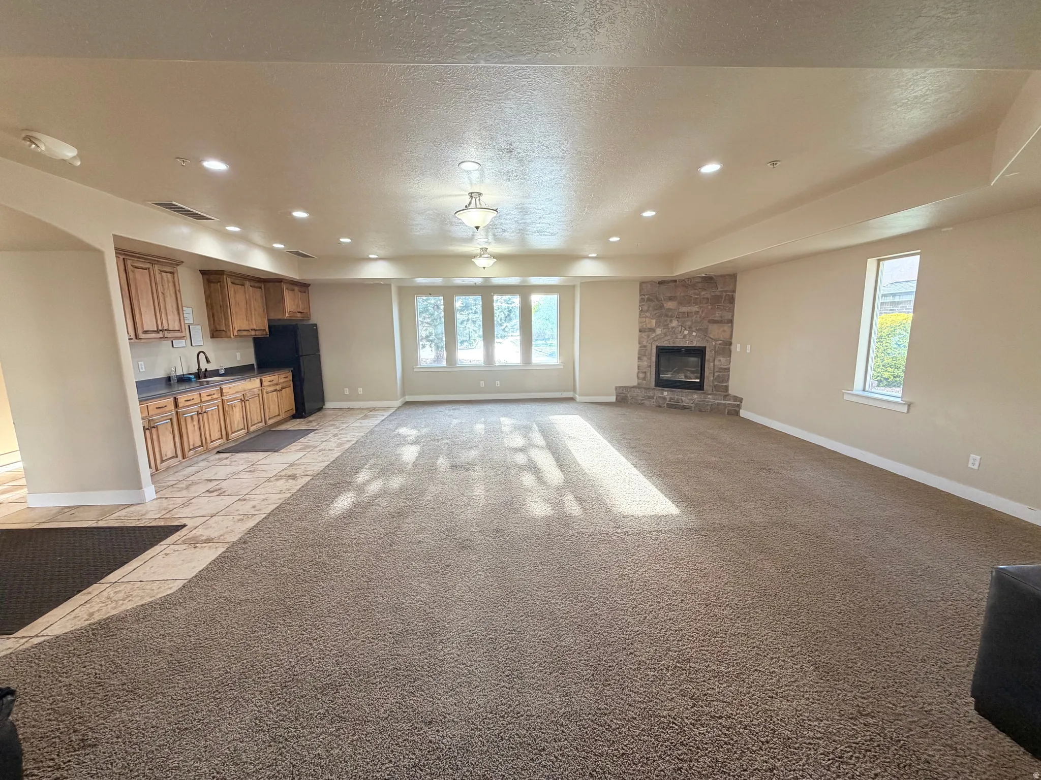 Unfurnished living room with recessed lighting, light colored carpet, a textured ceiling, and a fireplace